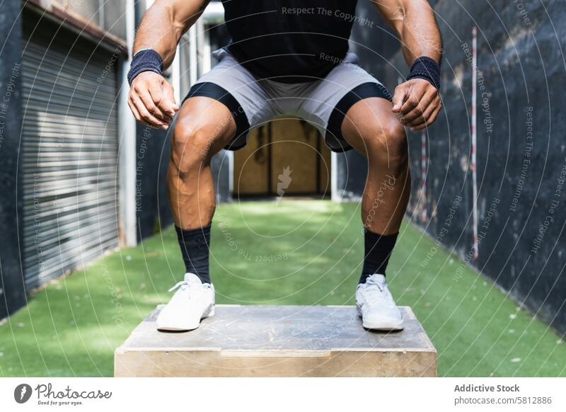 Anonymer ethnischer Sportler, der auf eine Holzkiste springt Mann Athlet springen Kasten Übung operativ Training Fitness Aktivität Gesundheit männlich aktiv
