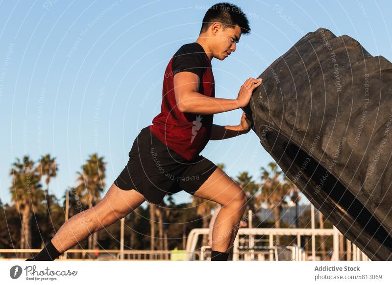 Starker Mann macht Reifenflip-Übung Sportler Flip Training stark asiatisch ethnisch Fitness sportlich Athlet Lifestyle Wellness Wohlbefinden männlich Vitalität