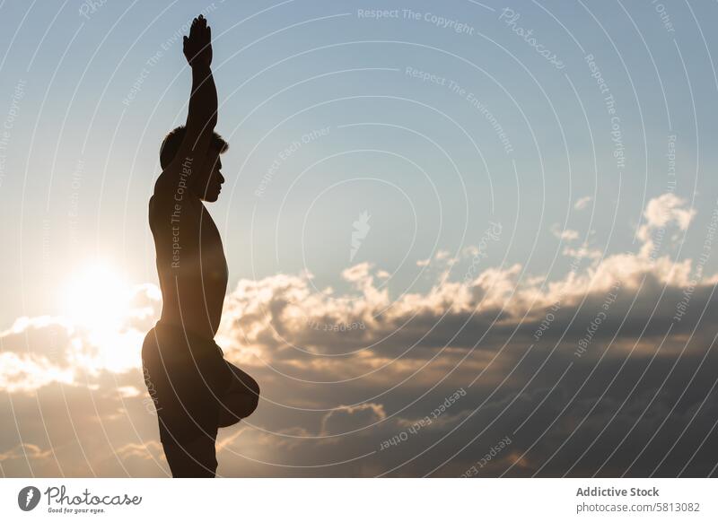 Mann übt Yoga-Asana bei Sonnenuntergang Baumhaltung vriksasana Silhouette üben Pose Gleichgewicht Harmonie Zen stehen männlich Lifestyle Wellness Wohlbefinden