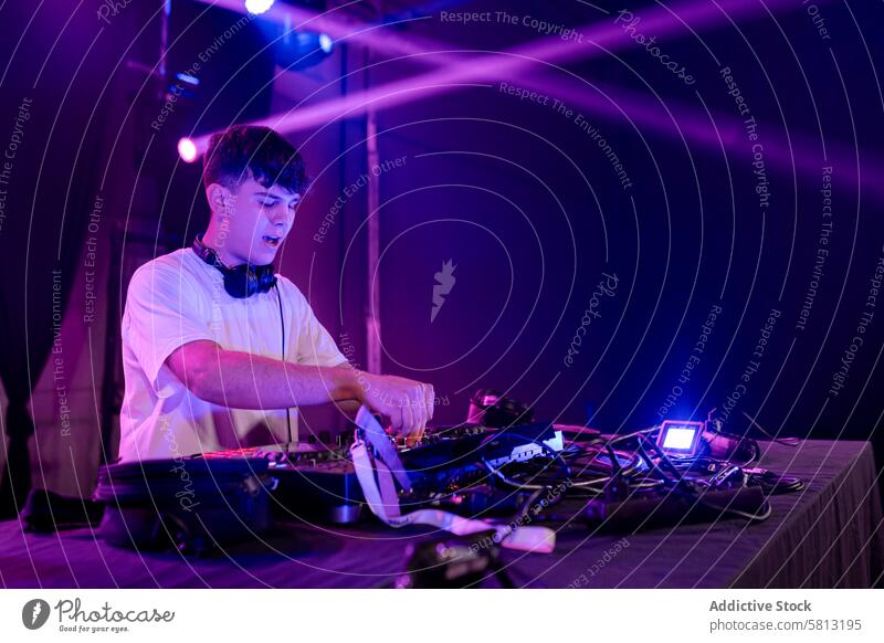 Junger DJ bei der Arbeit am Mischpult Mann junger DJ Disco dj männlich lässig Mischen Holzplatte purpur neonfarbig Lichter Nacht Musik Entertainment Club Tanzen