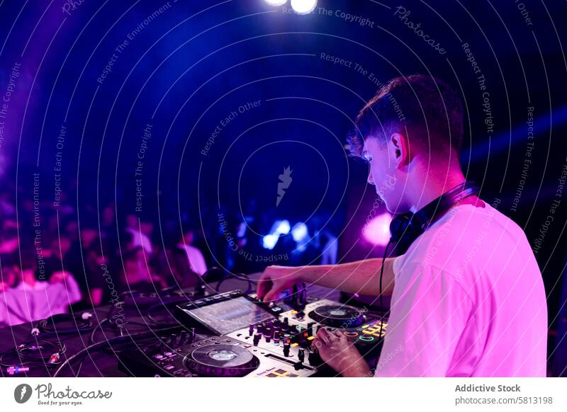 Rückansicht eines DJs bei der Arbeit in einer Diskothek Seitenansicht Textfreiraum Mann jung lässig Kaukasier Disco Konzert ausführen mischen Party dj