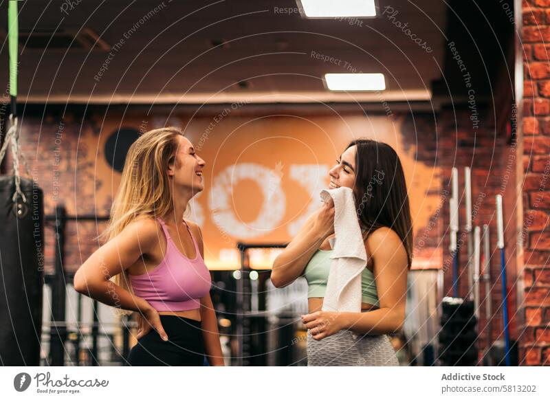 zwei junge Frauen unterhalten sich in der Turnhalle, während sie sich ausruhen Fitnessstudio Training Sport Lifestyle sprechend Pause Menschen Übung Gesundheit