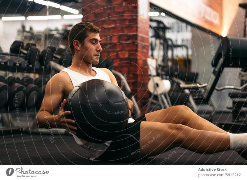 Junger Mann beim Hantelballtraining in einem Fitnessstudio jung Training Ball Bauchmuskeln passen muskulös Übung Gewicht Sport Erwachsener Lifestyle Stärke