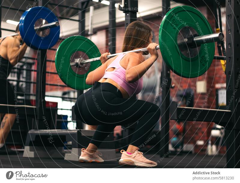Rückenansicht einer Sportlerin bei Kniebeugen in einer Turnhalle Fitnessstudio Training Übung Frau Athlet passen jung stark Gesundheit sportlich Körper Stärke