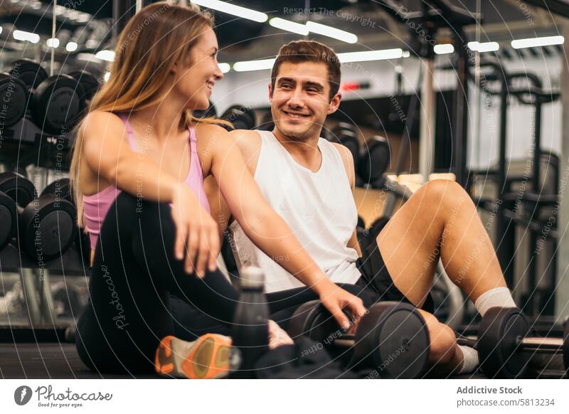 Mann und Frau Übung Training im Fitnessstudio Fitness brechen entspannen mit Hantel auf dem Boden sportlich aussruhen Pause stark Aktivität sprechend Trainerin