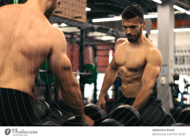 starker Mann vor dem Spiegel stehend mit Hanteln in einem Fitnessstudio muskulös Kraft Bodybuilder Muskel Gesundheit Gewicht Training Körper Übung Athlet Sport