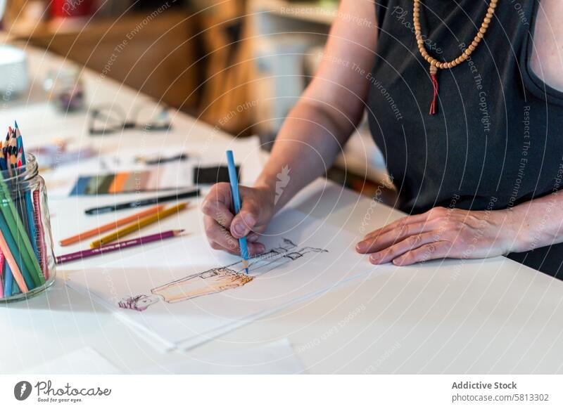 Hoher Winkel eines Modedesigners, der eine Modeskizze mit bunten Bleistiften zeichnet 50s oben Bekleidung Selbstvertrauen selbstbewusst Kreativität Design