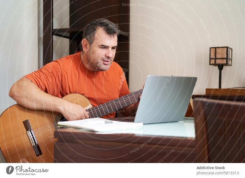 ein Mann mit Laptop im Online-Gitarrenunterricht, der Harmonielehre lernt online Schulunterricht Lernen Oberschwingungen Musiker Musical Sitzen Erwachsener