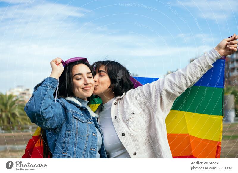 LGBTQ+ Freunde genießen einen Tag im Freien Freundschaft lgbtq+ Stolz Regenbogenflagge Zuneigung Kuss Wange Jeansjacke Liebe Vielfalt inklusive Freude