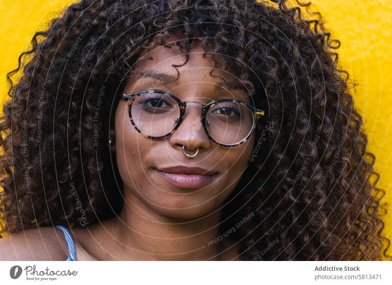 Trendige ethnische Frau vor heller Wand Stil Straße Großstadt gelb Kleid Brille jung krause Haare schwarz Afroamerikaner trendy urban lebhaft Zeitgenosse Mode