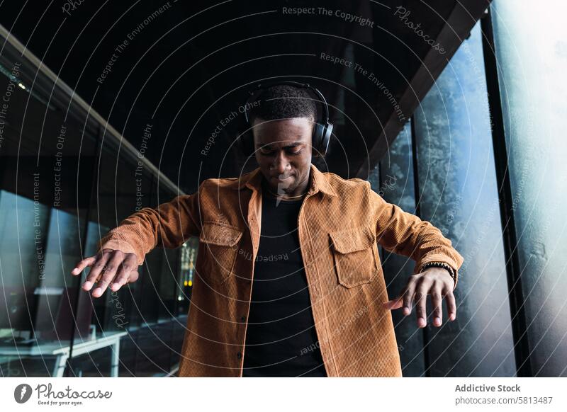 Schwarzer Mann hört Musik in der Nähe eines Gebäudes Kopfhörer Tanzen Straße Stil Gesang Melodie Zeitvertreib schwarz Afroamerikaner männlich zuhören Großstadt