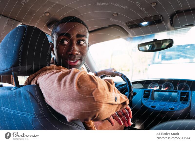 Schwarzer Fahrer beim Rückwärtsfahren im Auto Mann PKW im Innenbereich Automobil modern Lenkrad schwarz Afroamerikaner Verkehr trendy Stil Straße Vorschein
