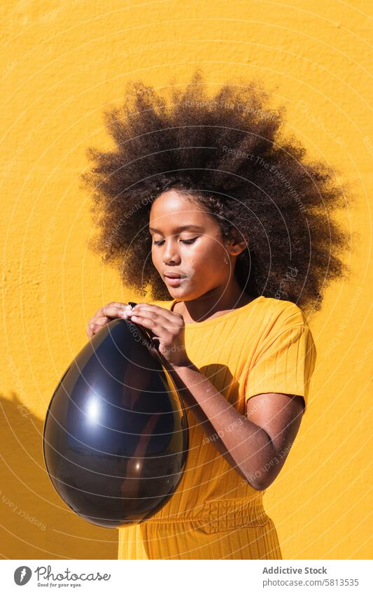 Schwarzes Mädchen bläst Partyballon Luftballon Schlag schwarz gelb Afro-Look krause Haare farbenfroh Farbe lebhaft aufblasen Kind Teenager Frisur ethnisch