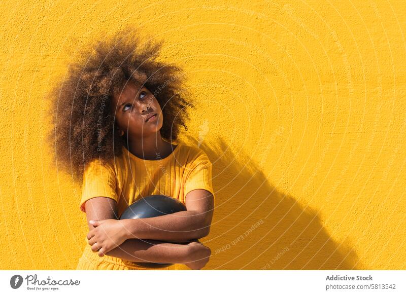 Schwarzes Mädchen hält Party Ballon Luftballon schwarz gelb Afro-Look krause Haare farbenfroh Farbe lebhaft aufblasen Kind Teenager Frisur ethnisch