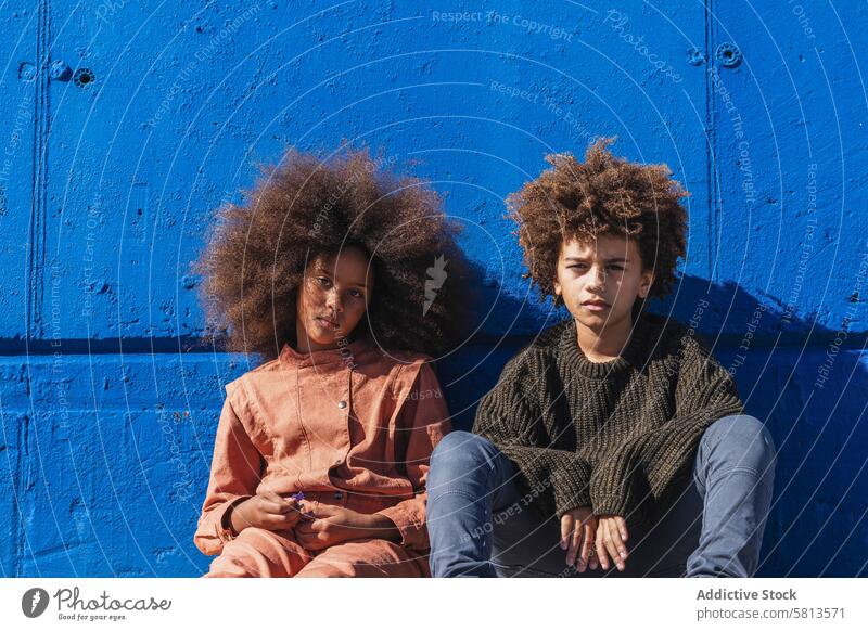 Schwarzer lockiger Junge und Mädchen ruhen in der Nähe der Mauer auf der Straße Kind Afro-Look Hipster Zusammensein Freund krause Haare Teenager Behaarung