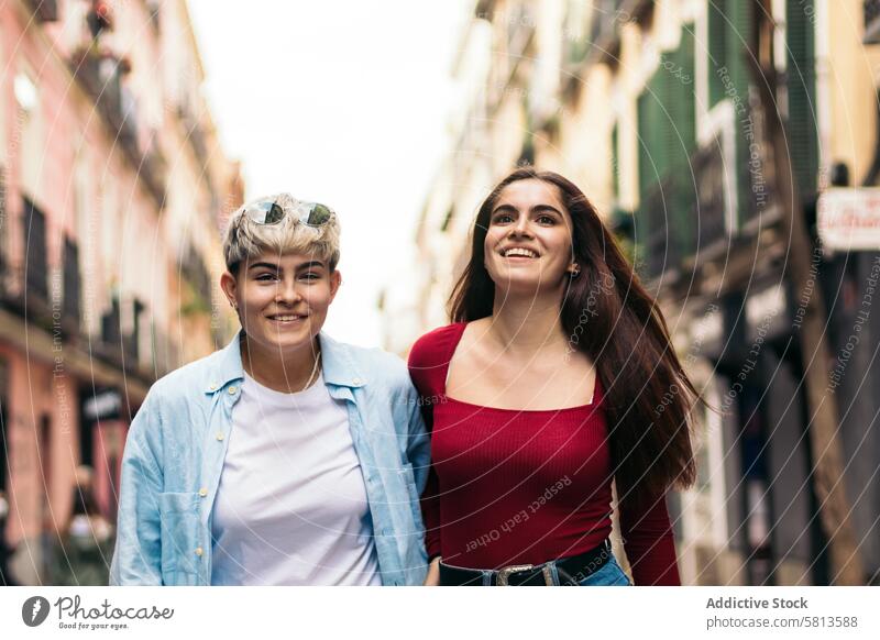 Zwei Teenager-Mädchen, die lächelnd auf einer Straße spazieren gehen. Vorderansicht jung zwei Lifestyle Menschen Sommer urban Mode Frau Glück im Freien