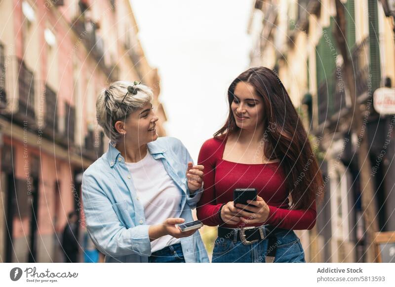 zwei Teenager-Mädchen, die spazieren gehen und ihre Handys benutzen laufen im Freien Mitteilung heiter Internet jung sprechend Menschen Familie Zwei Personen