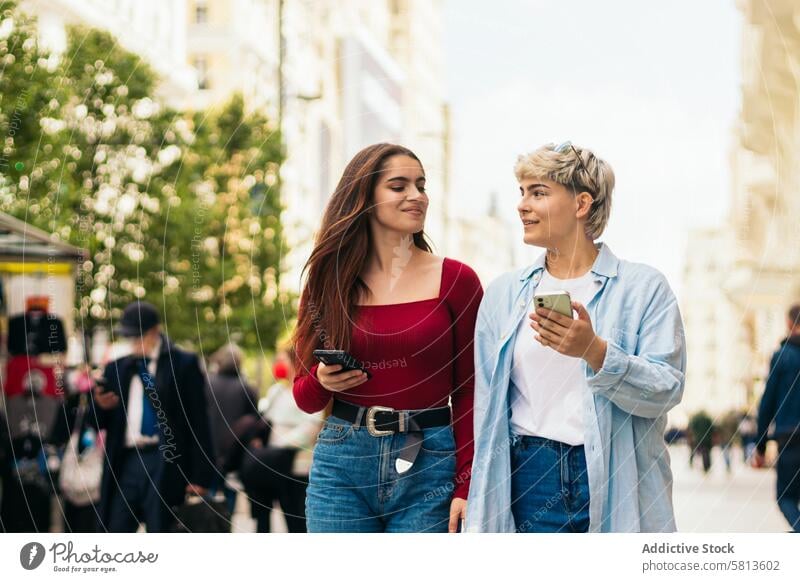 zwei Teenager-Mädchen, die spazieren gehen und ein Handy benutzen Mobile Telefon Smartphone Menschen jung Frau laufen Technik & Technologie benutzend