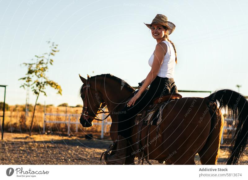 Junge Frau mit Hut reitet auf einem Pferd in der Landschaft bei Sonnenuntergang Natur jung Tier Ranch Cowgirl Cowboy Person pferdeähnlich Reiten schön Reiterin