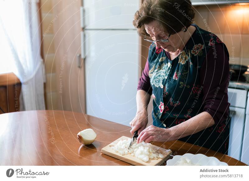 Alte Frau hackt Zwiebeln, um Kroketten zu Hause zuzubereiten alt zerkleinernd heimwärts Essen zubereiten Vorbereitung Küche Messer Senior Lebensmittel