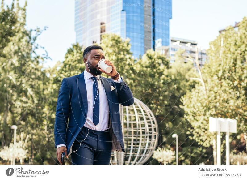 Schwarzer Geschäftsmann im Anzug verlässt das Büro, hält sein Smartphone und trinkt einen Kaffee Business Sitzung professionell Exekutive Erfolg Unternehmer
