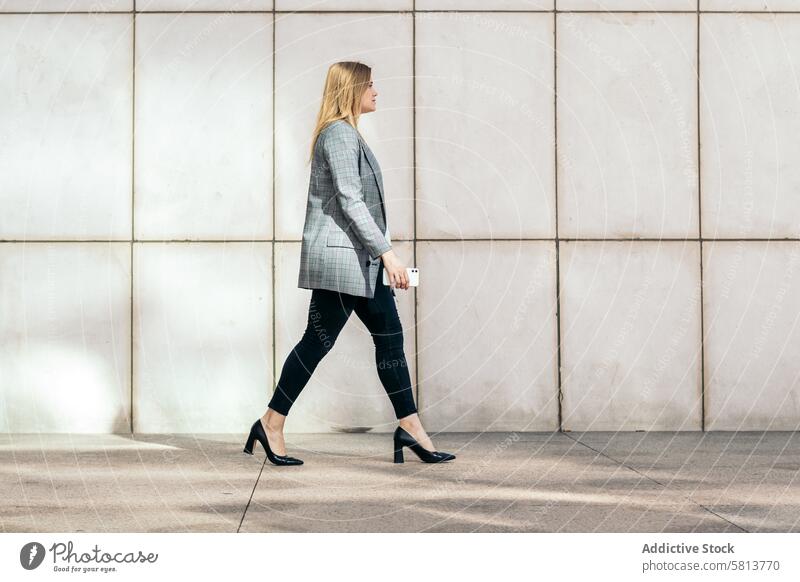 Seitenansicht einer Geschäftsfrau in Anzug und Stöckelschuhen auf dem Weg ins Büro Fersen professionell Karriere Mode Arbeitsweg Erfolg Selbstvertrauen Kraft