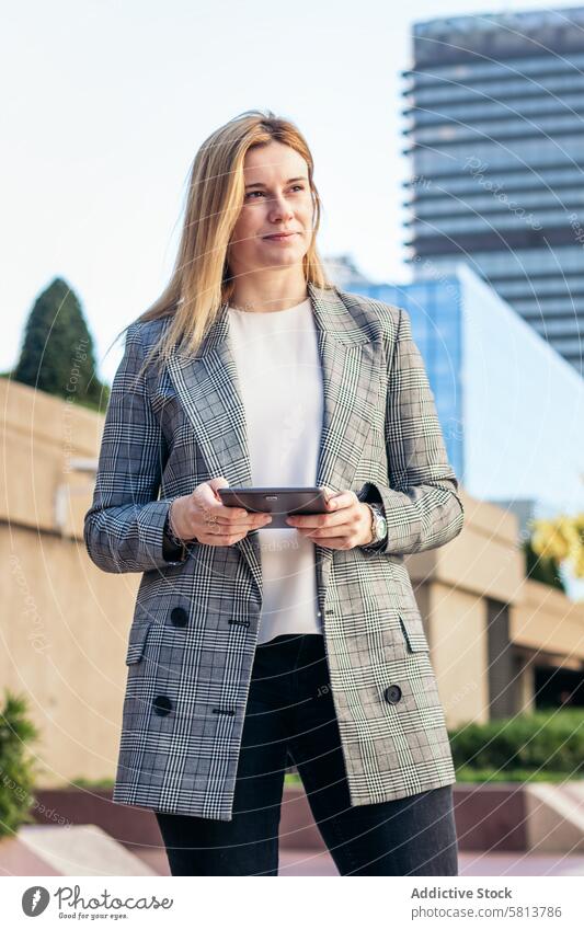 Fokussierte blonde Geschäftsfrau im Anzug, die draußen ein Tablet benutzt und lächelt Business Sitzung Team professionell Exekutive Erfolg Unternehmer Finanzen