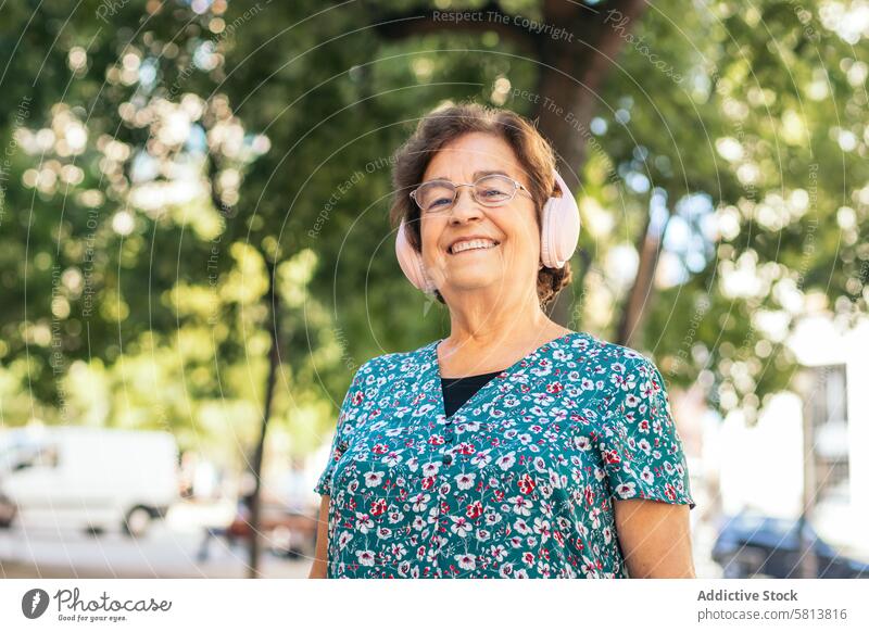 Ältere Frau geht die Straße entlang und hört Musik stylisch Senior Lifestyle alt Menschen Geschäftsfrau Kaukasier Technik & Technologie Glück Dame Holunderbusch