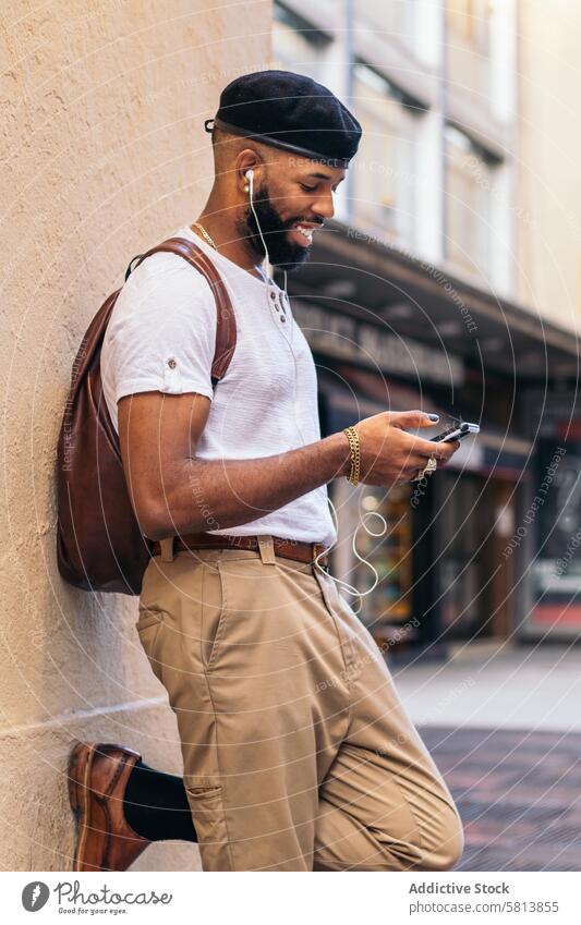Stilvoller schwarzer Mann, der sein Smartphone benutzt und draußen in der Stadt Musik hört Technik & Technologie Lifestyle Großstadt jung Straße urban Telefon
