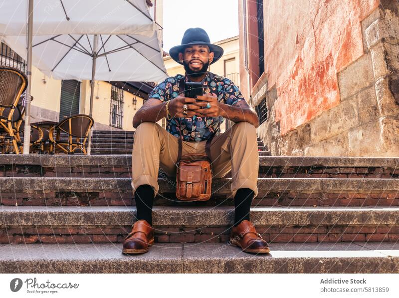 Stilvoller schwarzer Mann auf der Straße in der Stadt mit Smartphone Technik & Technologie Lifestyle Großstadt jung urban Telefon Mobile männlich Person