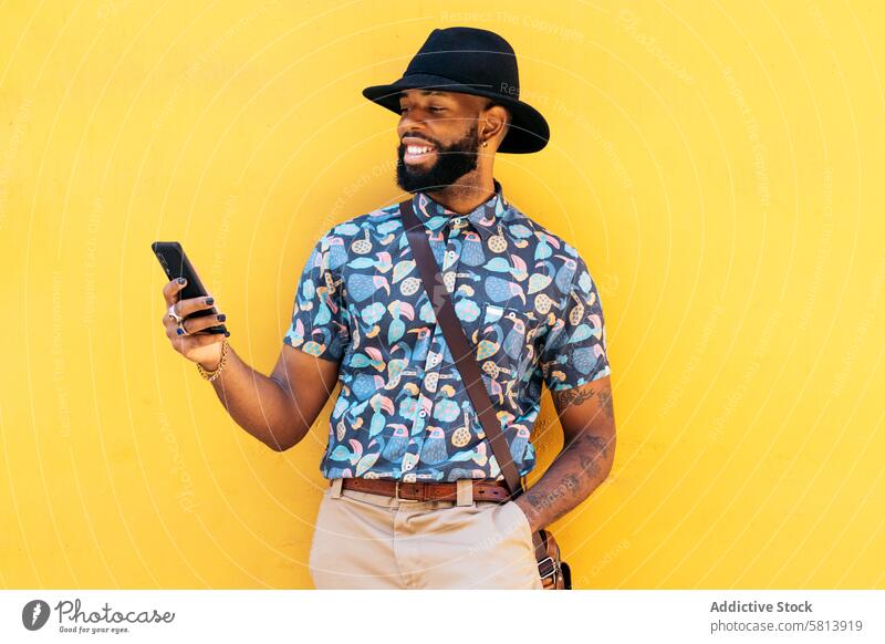 Stilvoller schwarzer Mann mit Smartphone im Freien auf gelbem Hintergrund Technik & Technologie Lifestyle Großstadt jung Straße urban Telefon Mobile männlich