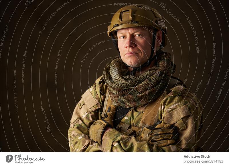 Porträt eines Airsoft-Soldaten in Tarnkleidung mit verschränkten Armen Armee Militär Mann bewaffnet Tarnung Krieg Waffe Gefecht speziell Gewehr Schutzhelm