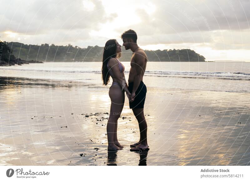 Junges Paar steht am Strand bei Sonnenuntergang Liebe Zusammensein Mann Romantik Glück Menschen jung zwei Meer romantisch Frau Urlaub Liebespaar Partnerschaft
