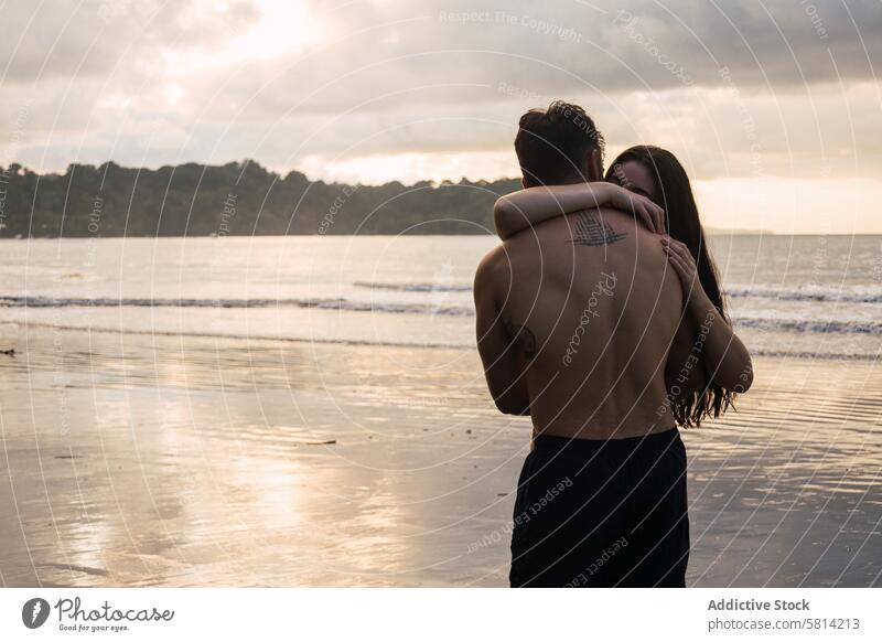 Junges Paar umarmt sich am Strand bei Sonnenuntergang Liebe Zusammensein Mann Romantik Glück Menschen jung zwei Meer romantisch Frau Urlaub Liebespaar
