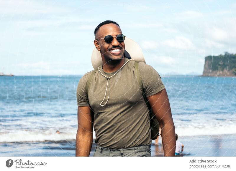 Schwarzer Mann mit Sonnenbrille am Strand schwarz männlich jung Hintergrund Typ stylisch Urlaub Glück reisen Porträt Lifestyle cool Lächeln gutaussehend