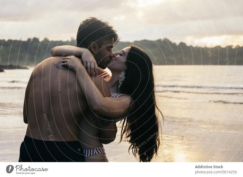 Küssendes Paar am Strand bei Sonnenuntergang Liebe Zusammensein Mann Romantik Glück Menschen jung zwei Meer romantisch Frau Urlaub Liebespaar Partnerschaft Kuss