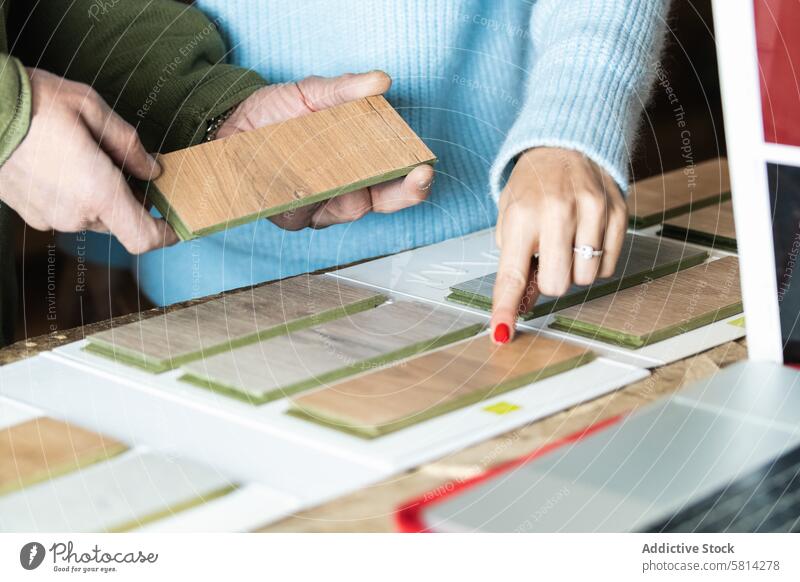 Anonyme Frau, die mit einem Schreiner in der Werkstatt ein Muster auswählt Mann Kunstgewerbler Klient Probe wählen Orden Hilfsbereitschaft Tischlerarbeit