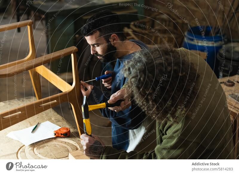 Männliche Kunsthandwerker stellen in einer Werkstatt Holzmöbel her Männer Zimmerer Kollege Hammer Schraubendreher Tischlerarbeit Möbel Stuhl Arbeit Holzarbeiten