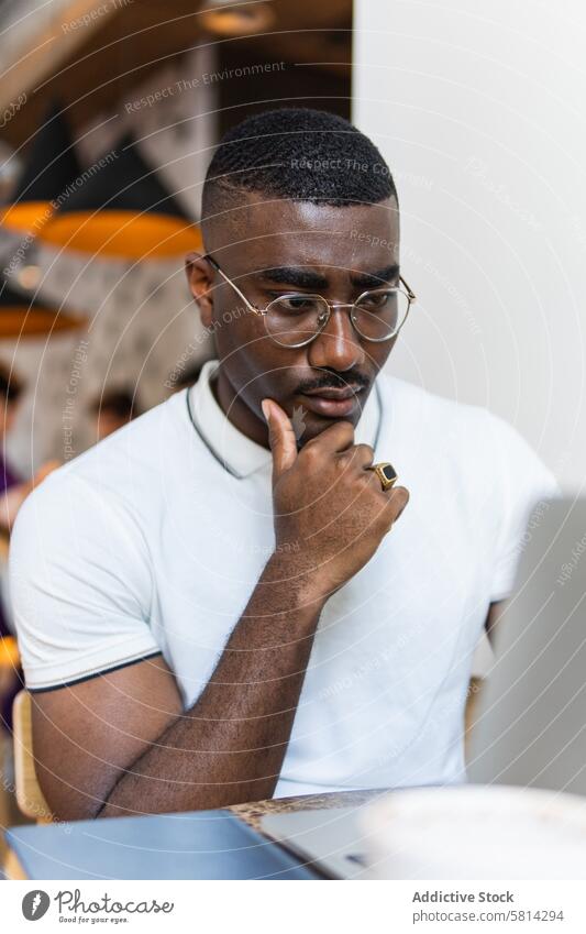 Ernster afroamerikanischer Mann mit Laptop am Tisch in einem Café nachdenklich Tasse trinken Brille modern ernst Afroamerikaner schwarz männlich Erwachsener