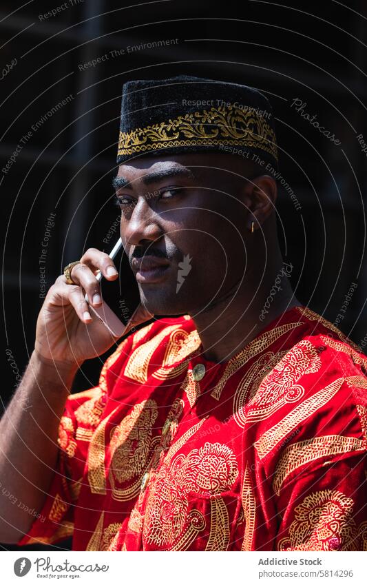 Afrikanischer Mann in traditioneller Kleidung telefoniert auf der Straße Telefonanruf Smartphone ernst Stadt Gebäude Tradition Kultur Kopfbedeckung schwarz
