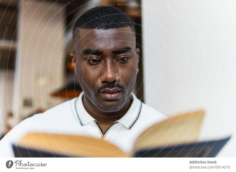 Ernster afroamerikanischer Mann, der in der Cafeteria ein Buch liest lesen Kantine allein ernst Hobby Roman nachdenklich Café Afroamerikaner schwarz männlich