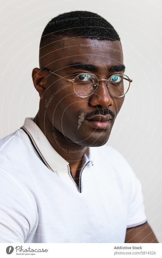 Ernster schwarzer Mann mit Brille auf weißem Hintergrund ernst Porträt Individualität selbstbewusst Studioaufnahme Schnurrbart T-Shirt allein Afroamerikaner