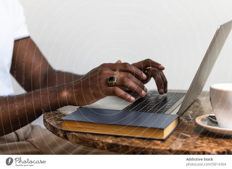 Afroamerikanischer Mann mit Laptop am Tisch in einem Café Tasse trinken modern Afroamerikaner schwarz männlich Erwachsener online Computer Lifestyle benutzend