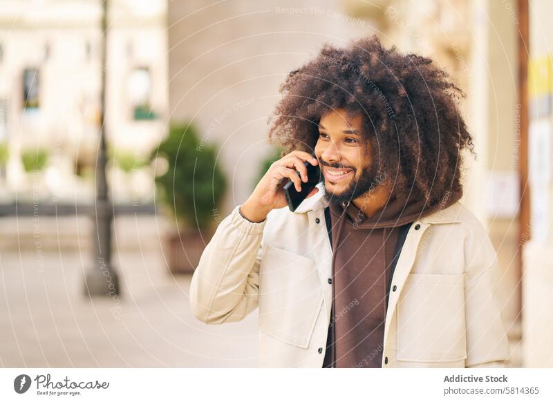 Porträt eines lächelnden jungen Mannes mit langen lockigen Haaren, der telefoniert Lächeln Afro-Look Behaarung sprechend Telefon Glück Person Erwachsener Mobile