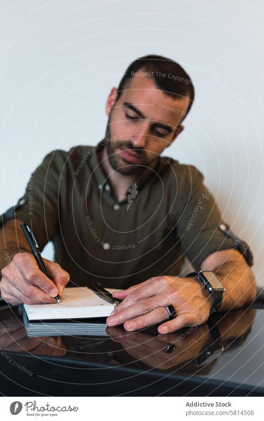 Mann schreibt in Notizbuch neben Laptop zur Kenntnis nehmen Notebook Notizblock schreiben Arbeit Arbeitsplatz Erinnerung Aufgabe männlich Tisch Gerät modern Typ