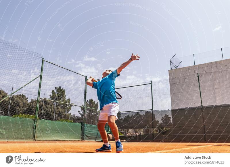 Kleiner Junge spielt Tennis auf einem unbefestigten Platz und macht einen Aufschlag Aktivität Sport Spiel Remmidemmi Kind Person Spieler spielen Athlet Training