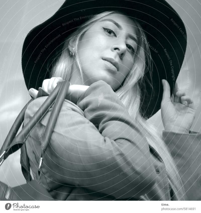 Frau mit Hut und Tasche feminin Portrait Hand Blick nach unten Blick in die Kamera Mantel blond langhaarig Bewegung beobachten Gesicht schauen lifestyle