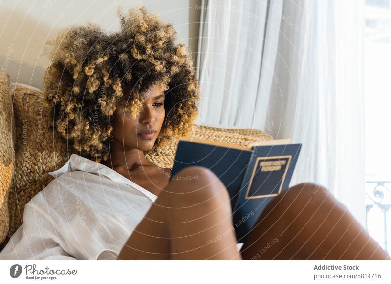 Junge schwarze Frau sitzt auf dem Bett und liest ein Buch lesen Hobby Schlafzimmer Morgen Wochenende Freizeit Literatur heimwärts Roman attraktiv zu Hause