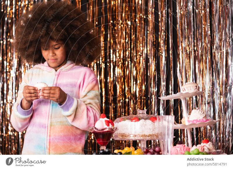 Nettes schwarzes Mädchen mit Donut im Zimmer mit Lametta-Streifen Krapfen Konditorei süß Dessert Leckerbissen Bonbon golden festlich ethnisch Afroamerikaner