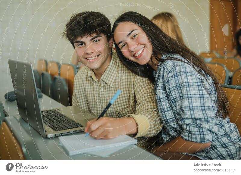 Glückliches Teenagerpaar während einer Vorlesung in der Universität Paar Schüler Lektion Lächeln schreiben Hinweis Zusammensein Bildung Porträt lernen fettarm